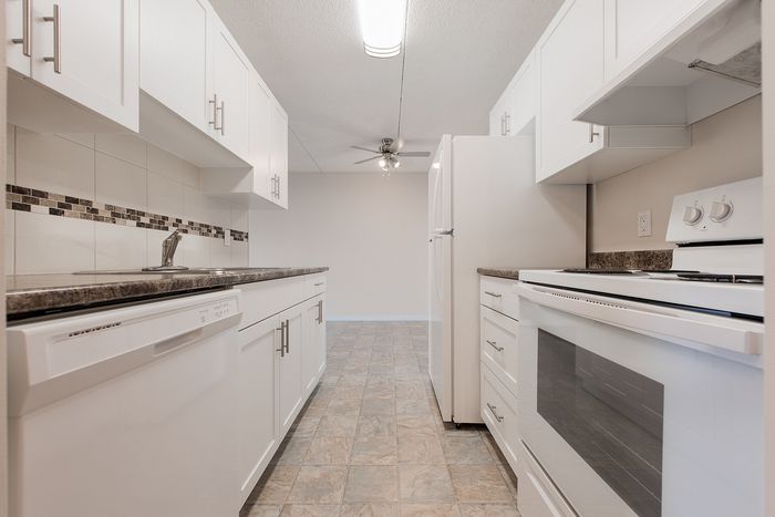 Modern kitchen with sleek white cabinets, granite countertops, and stylish tile backsplash.