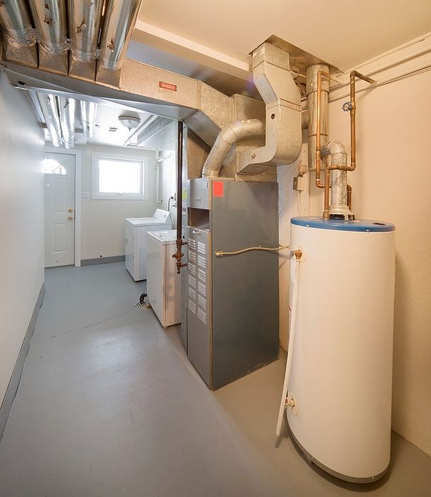 Modern basement utility room featuring essential HVAC equipment and laundry appliances, well-lit and spacious.