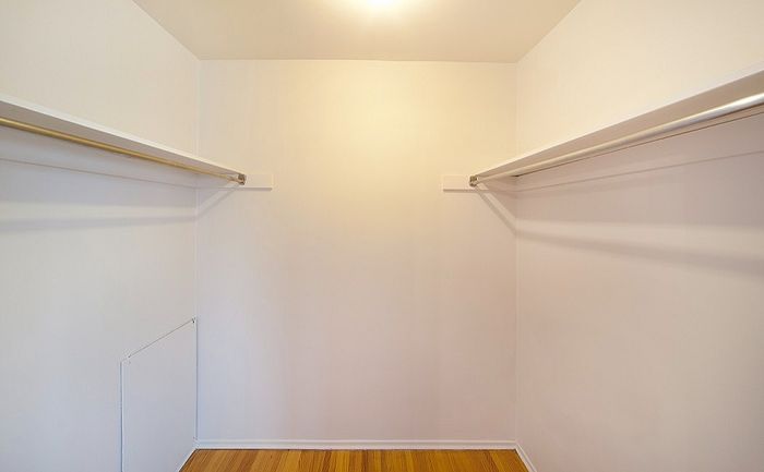 Spacious walk-in closet with wooden flooring and ample hanging space, perfect for organizing your wardrobe.