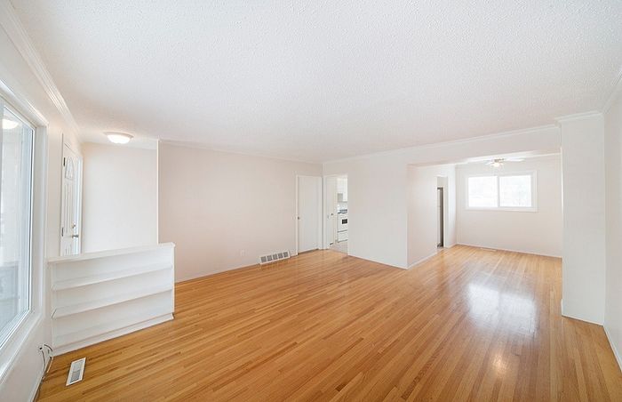 Bright and spacious living area with sleek hardwood floors and large windows, ideal for natural light and modern living.