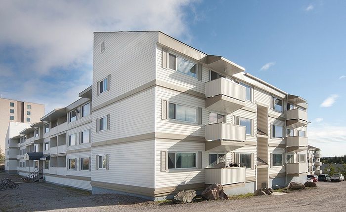 Modern apartment complex with spacious balconies and stylish white facade against a clear blue sky.