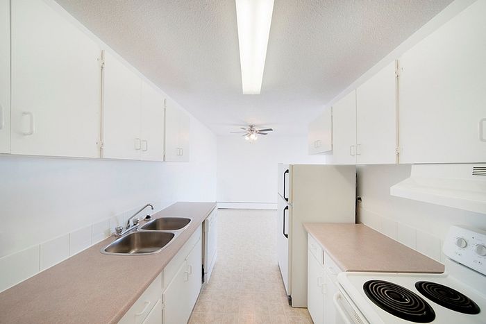 Bright, modern kitchen featuring white cabinetry, sleek countertops, and a spacious layout flowing into the living area, perfect for entertaining.