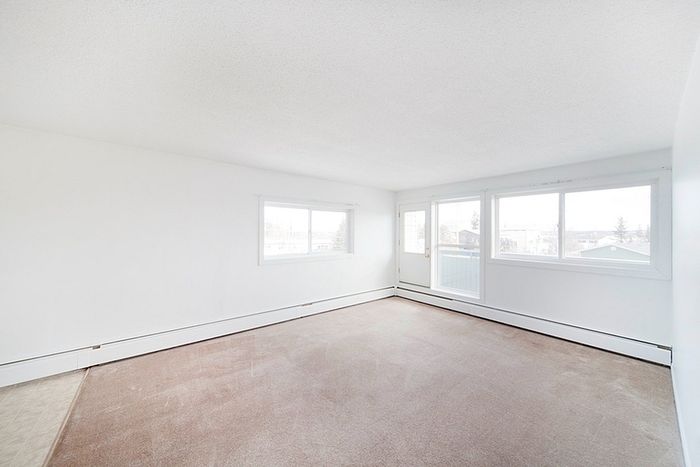 Bright and airy living space with large windows and soft beige carpet, perfect for a cozy home atmosphere.