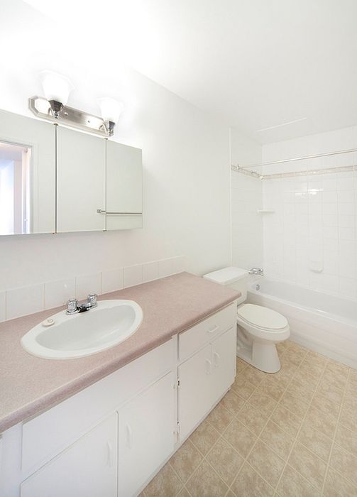 Bright and pristine bathroom featuring a sleek countertop, modern lighting, and a spacious bathtub.