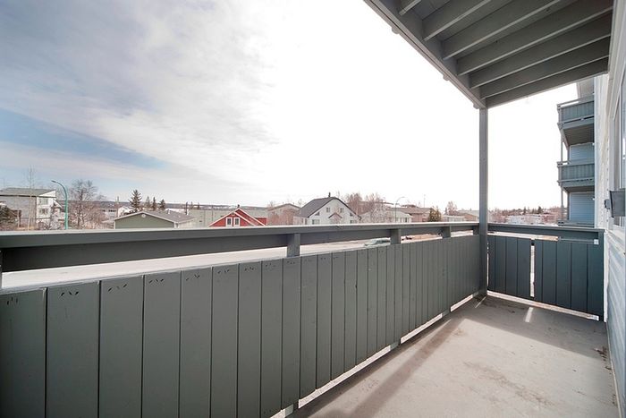 Charming apartment balcony offering a tranquil view over a suburban neighborhood, perfect for relaxation.