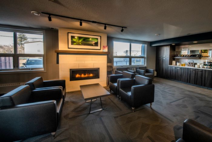 Cozy lounge area with elegant seating around a modern fireplace and a welcoming refreshment counter.