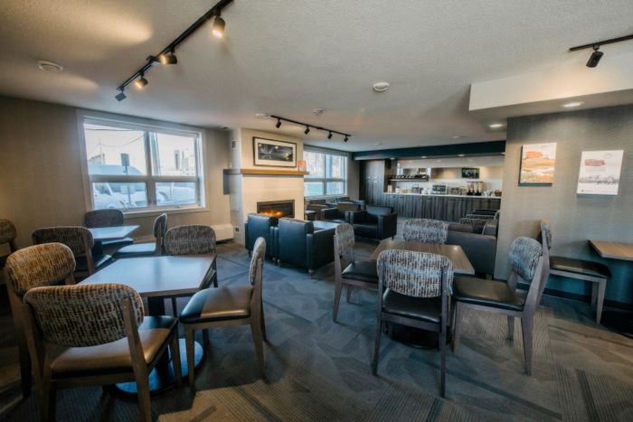 Modern lounge area featuring sleek seating, a cozy fireplace, and a stylish coffee station, perfect for relaxing and socializing.