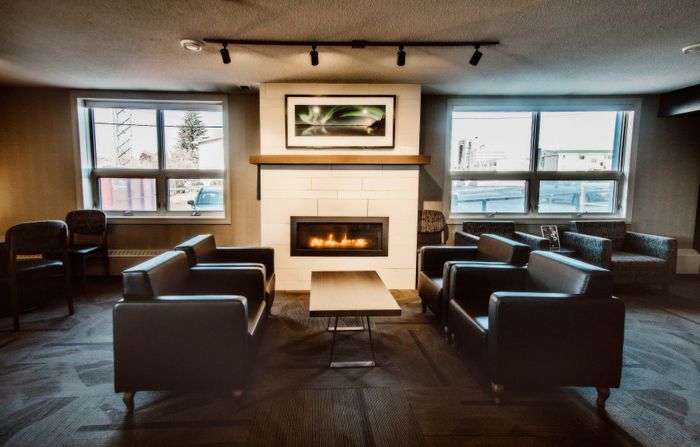 Cozy lounge area with modern armchairs, a centerpiece table, and a warm fireplace under elegant lighting.