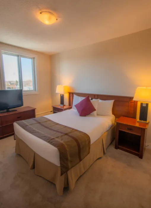 Cozy bedroom with a large bed, soft lighting, and a scenic view from the window, perfect for relaxing.