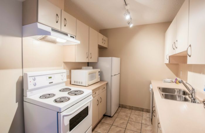 Sleek and modern kitchen featuring ample cabinetry, a pristine white stove, and a spacious countertop with double sinks.