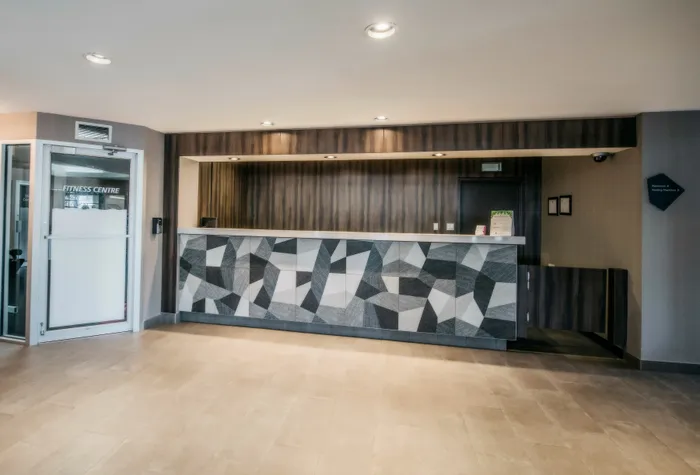 Elegant hotel lobby featuring a modern geometric reception desk and sleek design elements, creating a welcoming atmosphere.