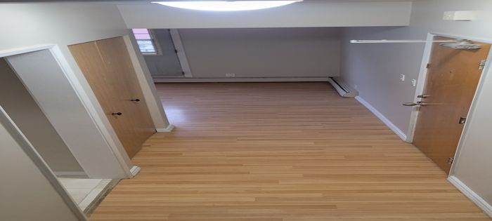 Inviting hallway with sleek wooden flooring, providing a warm and welcoming entrance with ample light.