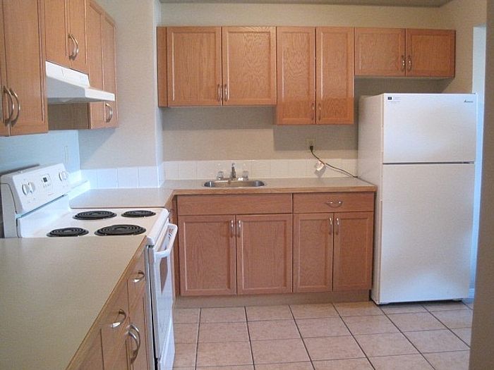 Modern kitchen with elegant wood cabinetry, tiled floor, and pristine white appliances for a contemporary living space.