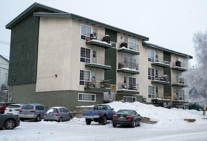 Charming multi-story apartment building with private balconies and ample parking, nestled in a serene snowy setting.