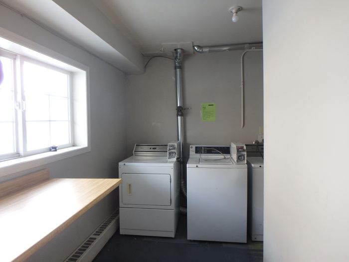 Bright laundry room with ample natural light, featuring modern washers, dryers, and a convenient folding table.