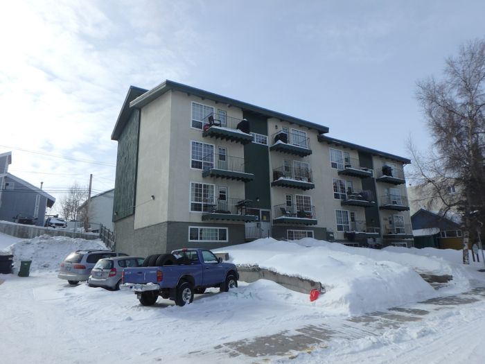Charming apartment building with private balconies, nestled in a serene snowy landscape, offering a cozy community vibe.