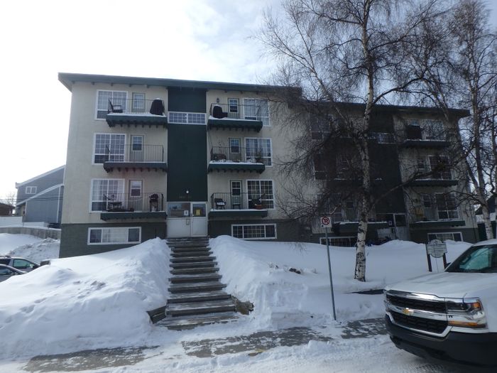 Cozy three-story apartment building with charming balconies, nestled in a snowy landscape, offering serene and comfortable living.