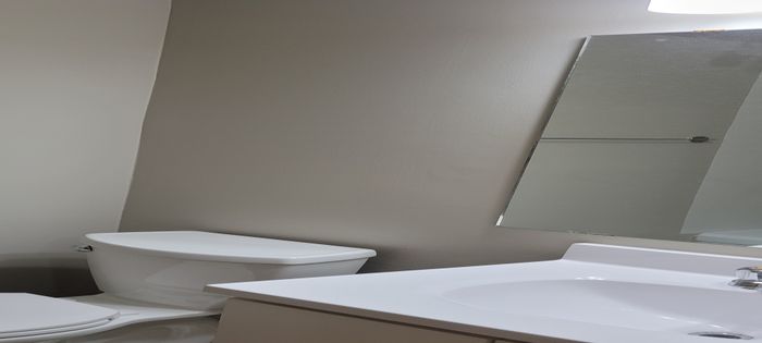 Sleek and modern bathroom with elegant fixtures, featuring a stylish vanity, large mirror, and pristine white toilet.