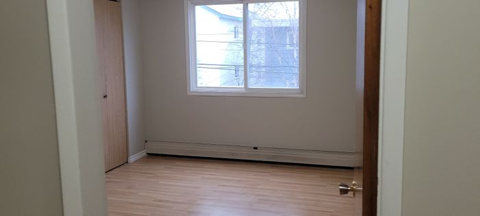 Bright bedroom with a large window, wooden floors, and a spacious closet, perfect for creating a cozy retreat.