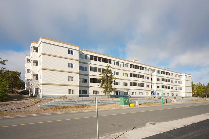 Bright and inviting multi-story apartment building with a modern facade, set against a backdrop of clear blue skies.