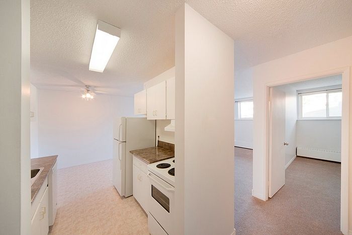 Bright and inviting kitchen leads to a cozy bedroom, showcasing modern appliances and ample natural light.