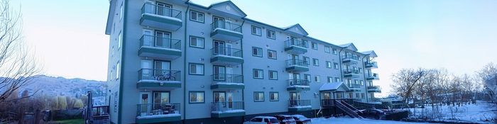 Charming apartment building with multiple balconies nestled in a serene winter landscape, perfect for cozy living.