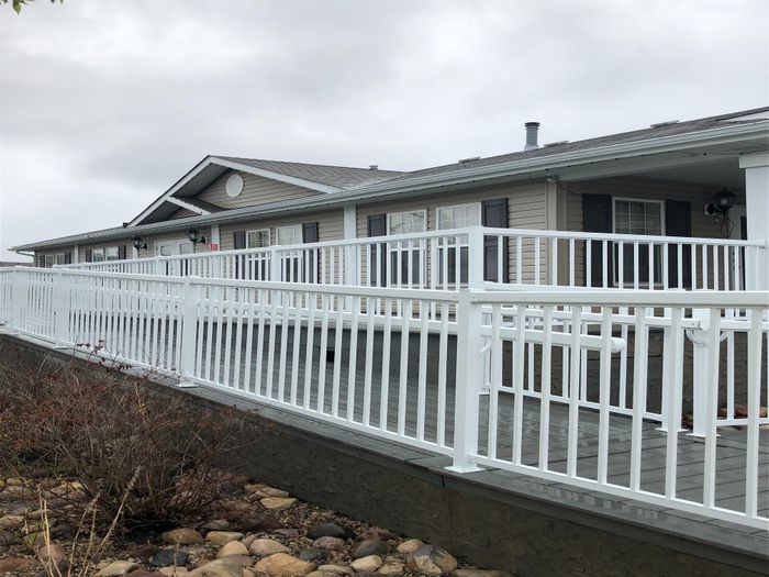 Charming single-story home with modern white railing, nestled in a serene setting with natural rock landscaping.