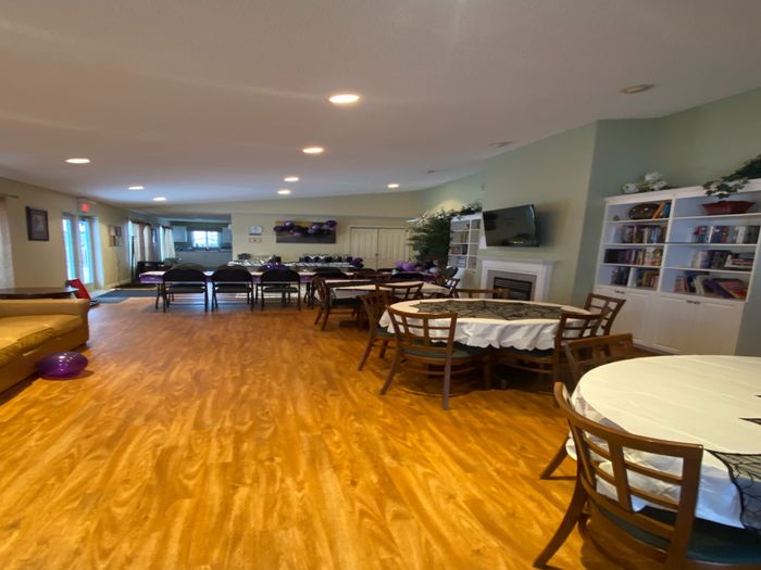 Inviting community room with elegant wood flooring, cozy fireplace, and ample seating perfect for gatherings.