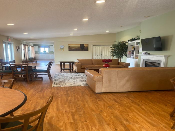Inviting open-concept living area with elegant wooden flooring, comfortable seating, and a modern kitchen in the background.