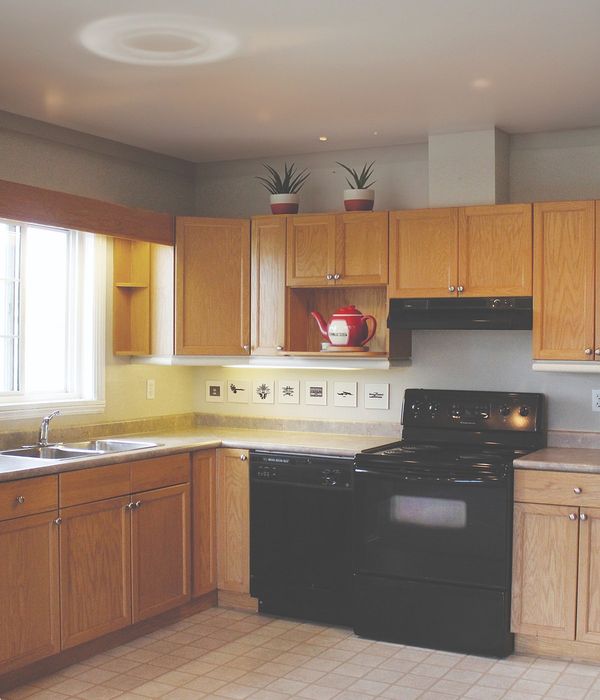 Charming kitchen with warm wooden cabinets, modern black appliances, and bright natural light, perfect for cooking and entertaining.
