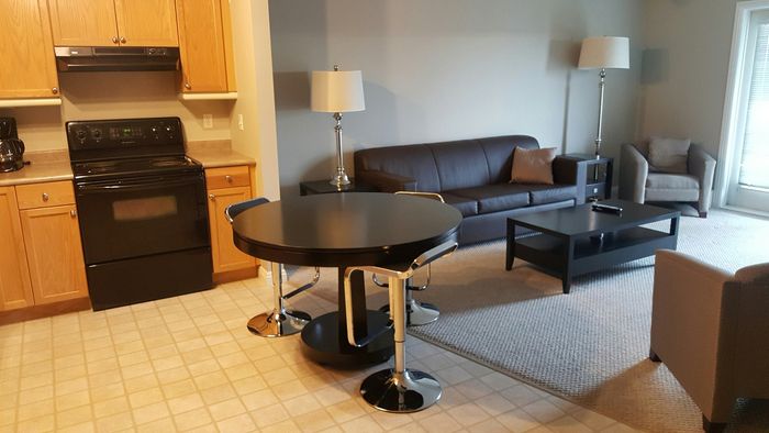 Inviting open-concept living space with a modern kitchen, sleek round dining table, and cozy seating area perfect for relaxation.