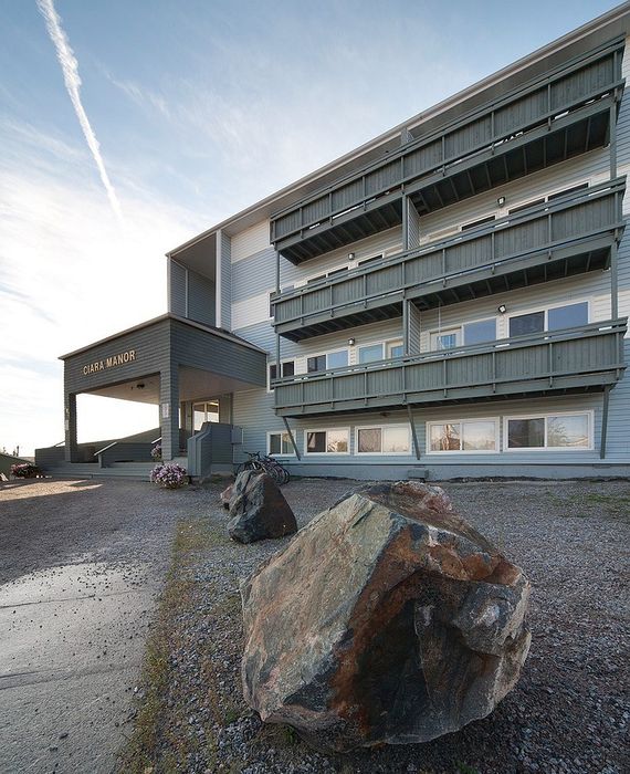 Charming multi-story building with spacious balconies set against a serene sky, featuring rustic stonework in the foreground.