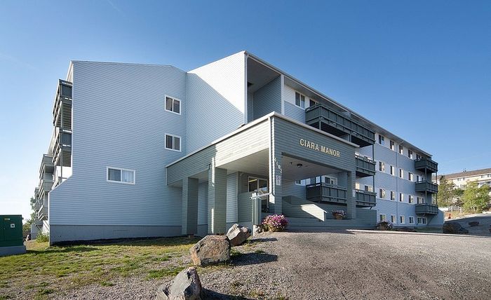 Elegant multi-story apartment building exterior with modern architecture and balconies, surrounded by scenic landscapes at Ciara Manor.