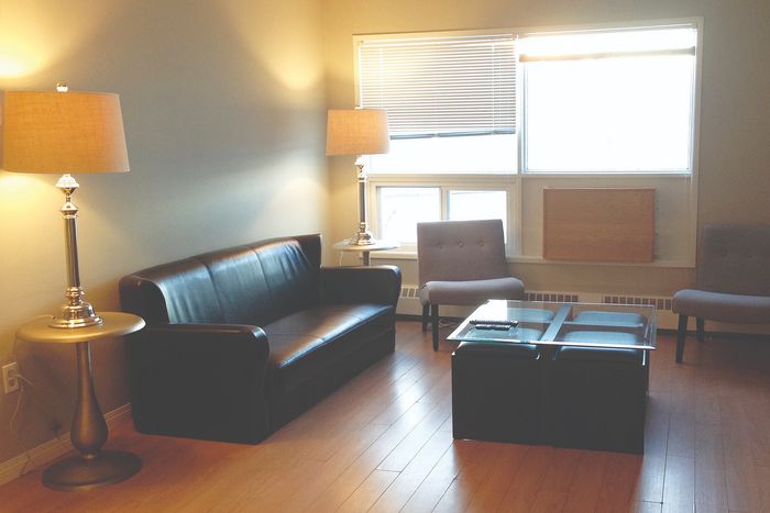 Cozy living room with elegant black leather couch, contemporary glass coffee table, and warm ambient lighting from stylish lamps.