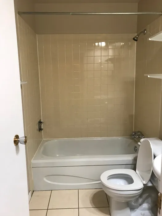 Charming bathroom featuring a pristine bathtub, elegant tile walls, and a modern toilet, perfect for relaxation and comfort.
