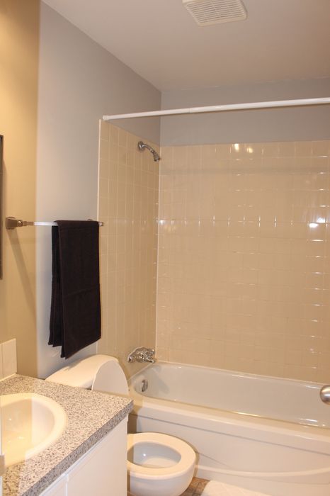 Bright, modern bathroom with a sleek tiled bathtub, elegant countertop, and cozy fixtures.