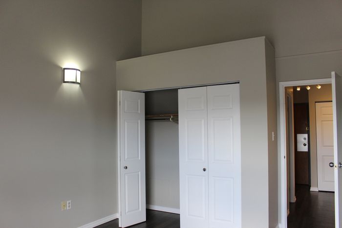 Bright and modern bedroom with sleek sliding closet doors and ambient wall lighting, offering a spacious and inviting atmosphere.