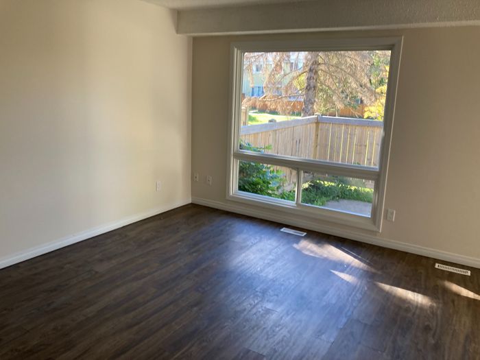 Bright and spacious living area with elegant hardwood flooring and a large window overlooking a lush garden.