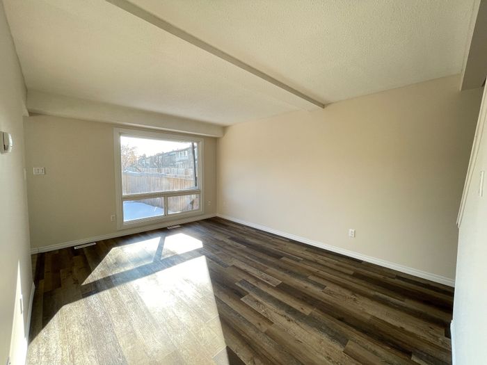 Bright and inviting living space with expansive window and elegant hardwood floors, offering abundant natural light.