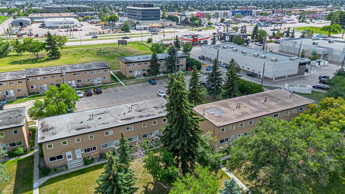 Expansive aerial view of a serene apartment complex surrounded by lush greenery and conveniently located near shopping and business centers.