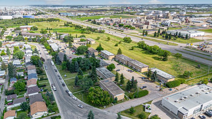 Inviting aerial view of a charming suburban neighborhood featuring tree-lined streets, modern apartment buildings, and lush green spaces, ideal for families and professionals.