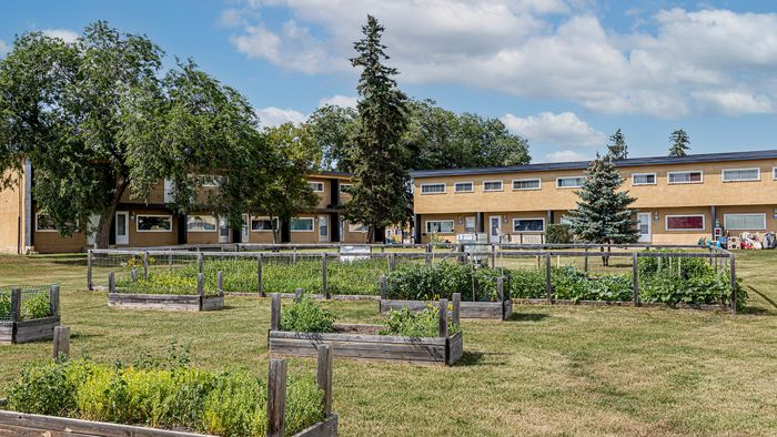 Charming apartment complex with lush community garden and vibrant greenery, offering a serene living environment.