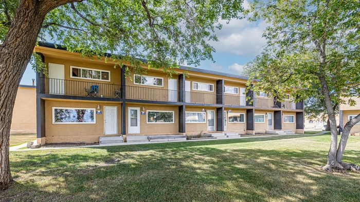 Charming two-story apartment building with private balconies and lush green surroundings, offering a serene living experience.