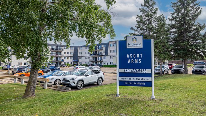Charming residential complex Ascot Arms under sunny skies, featuring well-maintained grounds, ample parking, and lush greenery.
