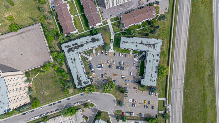 Vibrant aerial view of a well-designed apartment complex featuring ample parking, lush greenery, and modern infrastructure, perfect for comfortable urban living.