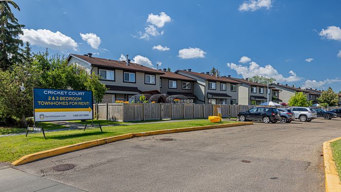 Charming townhomes at Cricket Court offering 2 and 3-bedroom rentals, featuring a lush community setting and convenient parking, under a clear blue sky.