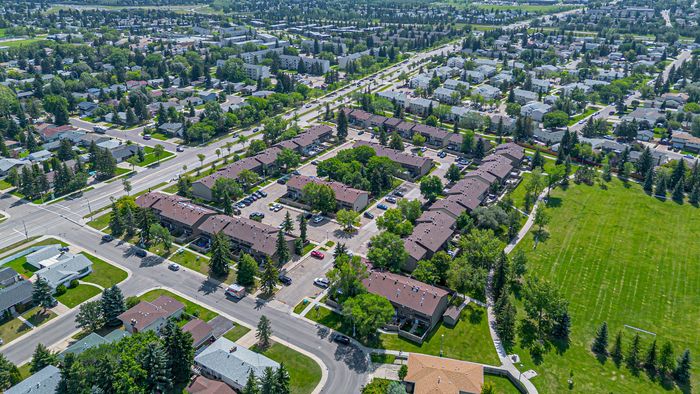 Vibrant aerial view of a tree-lined suburban neighborhood with charming homes, lush green spaces, and convenient access to roads.