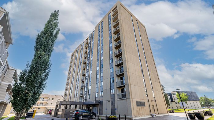 Modern high-rise apartment building with spacious balconies and vibrant urban surroundings on a sunny day.