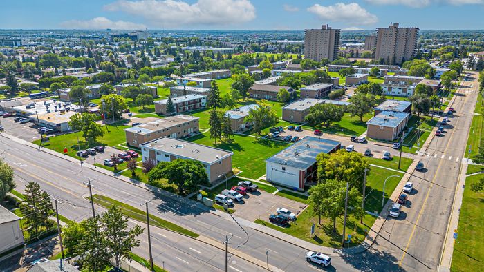 Vibrant aerial view of a thriving suburban neighborhood with spacious green areas, modern apartment buildings, and tree-lined streets, perfect for family living.
