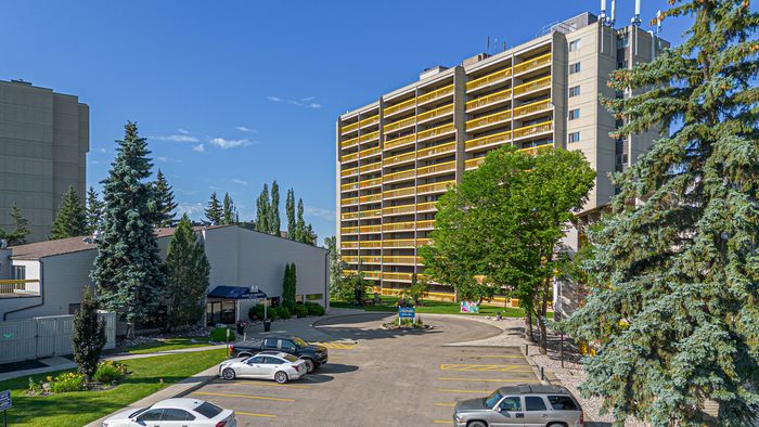 Vibrant high-rise apartment complex with balconies and ample parking, surrounded by lush greenery and modern architecture.